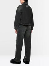 A model shown from the back wearing a black cropped denim jacket and dark gray wide-leg jeans, photographed against a clean white studio background.